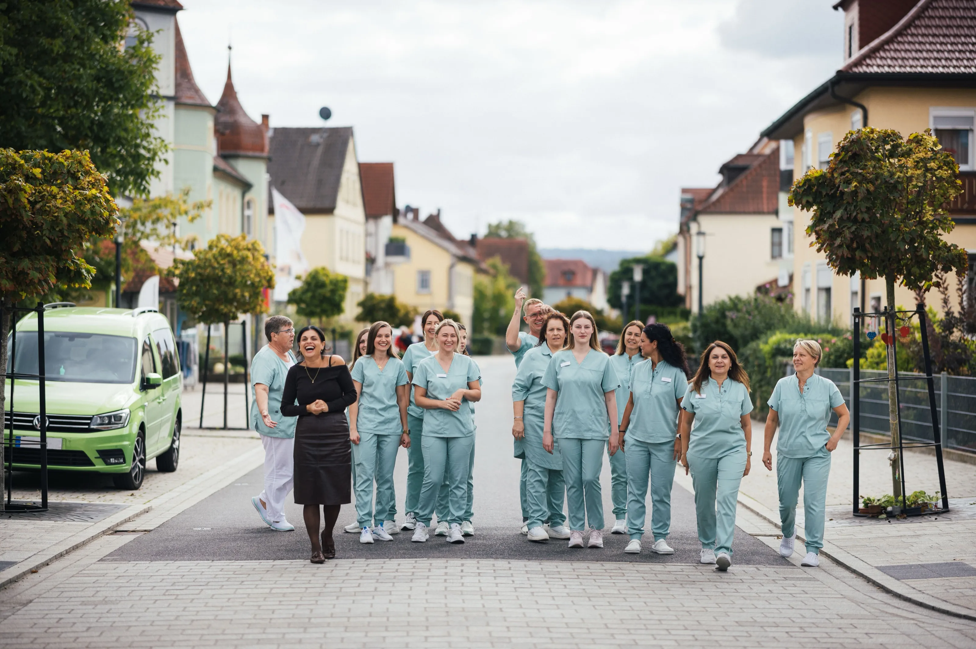 Das Praxisteam in mintfarbener Praxiskleidung läuft gemeinsam eine Straße entlang